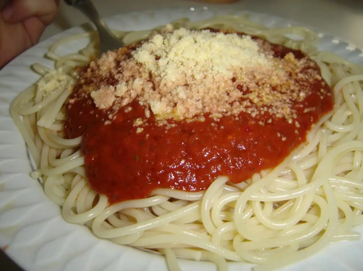 The image depicts a plate of spaghetti topped with a rich red tomato sauce and a generous amount of grated cheese with Season Canned Spaghetti