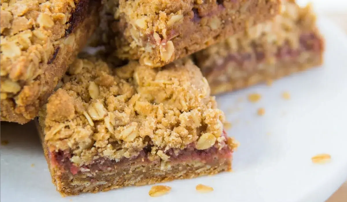 The image shows a close-up view of a stack of baked oat bars with a visible layer of fruit jam in the middle made by Wyse guide.