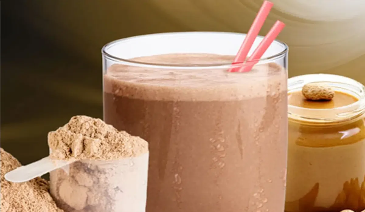 The image shows a chocolate-flavored Herbalife shake for weight loss and a jar of peanut butter with peanuts around it.