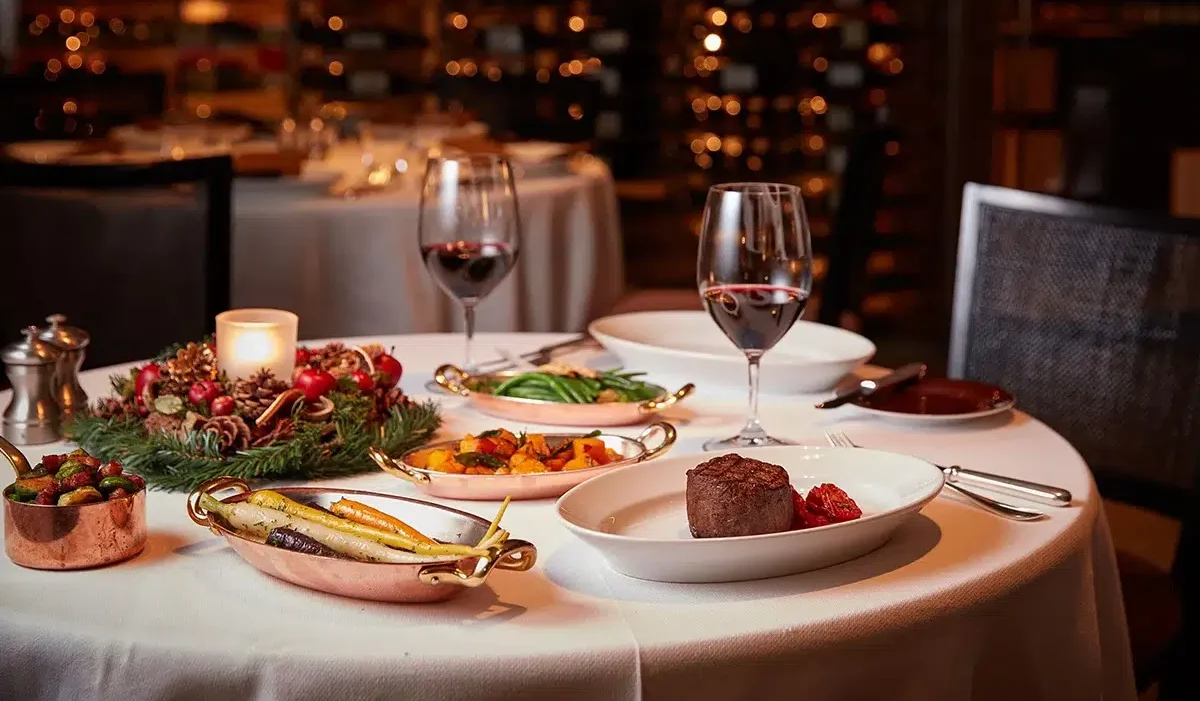 The image presents an Dinner for Tonight with set table in a cozy restaurant with a romantic ambiance, highlighted by warm, dim lighting and a wine cellar in the background