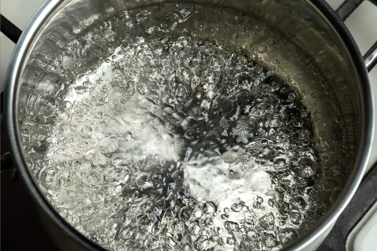 A stainless steel pot of boiling water on a gas stove.