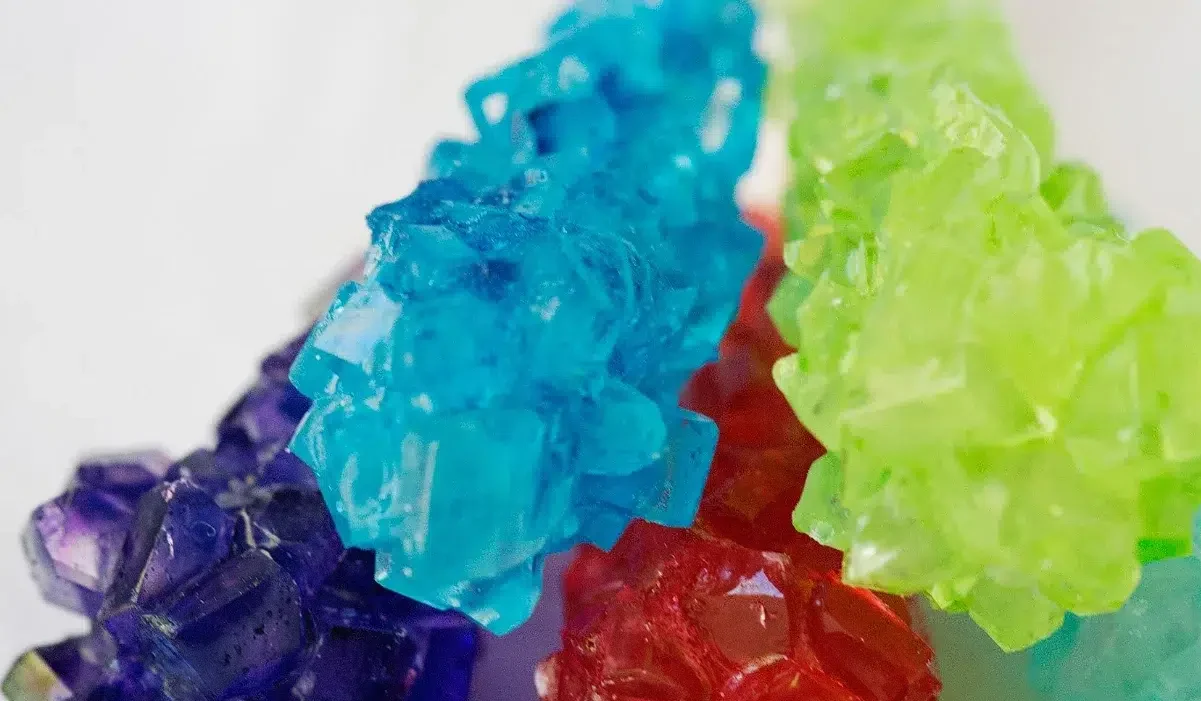 The image features a collection of vibrant, colored sugar crystals