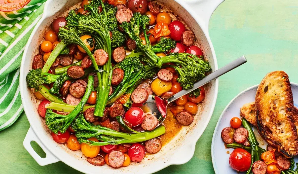 The image showcases a colorful and appetizing one-pan meal, consisting of sautéed broccolini, sliced sausage, and cherry tomatoes of various colors from meat church recipes