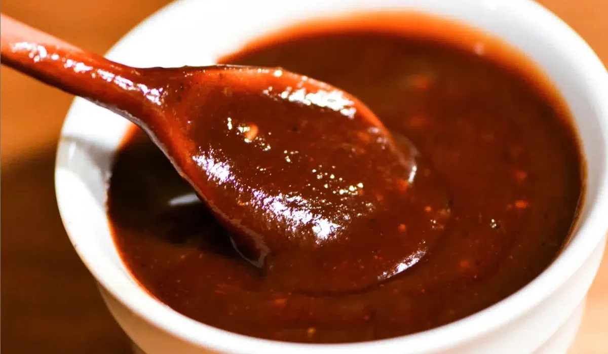 This is an image of a dark, rich Bloves sauce in a white bowl with a spoon lifting some out, indicating a thick and possibly sticky texture.