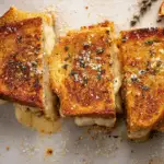 Garlic Bread Grilled Cheese cut in half with melty cheese pull