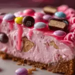 Pink M&M Snickers Cheesecake topped with candy