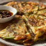 crispy Korean vegetable pancake with dipping sauce on a plate with dipping sauce