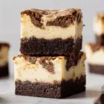 Brownie Bottom Cookie Dough Cheesecake Bars stacked on a plate